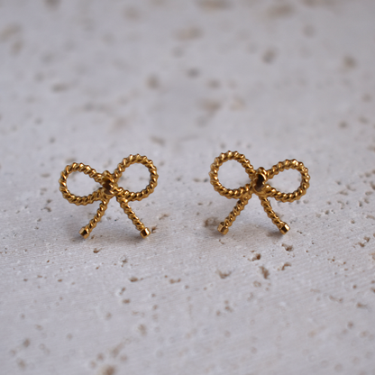 Waterproof Gold Plated Stainless Steel Bowtiful Earrings. Be bold and beautiful with these Bowtiful Earrings! Not only do they have a cute knot design, but they are also waterproof and won't tarnish. Stay stylish without worrying about the weather.

Material: Stainless Steel, 18K Gold Plated
Size: Length - 1cm